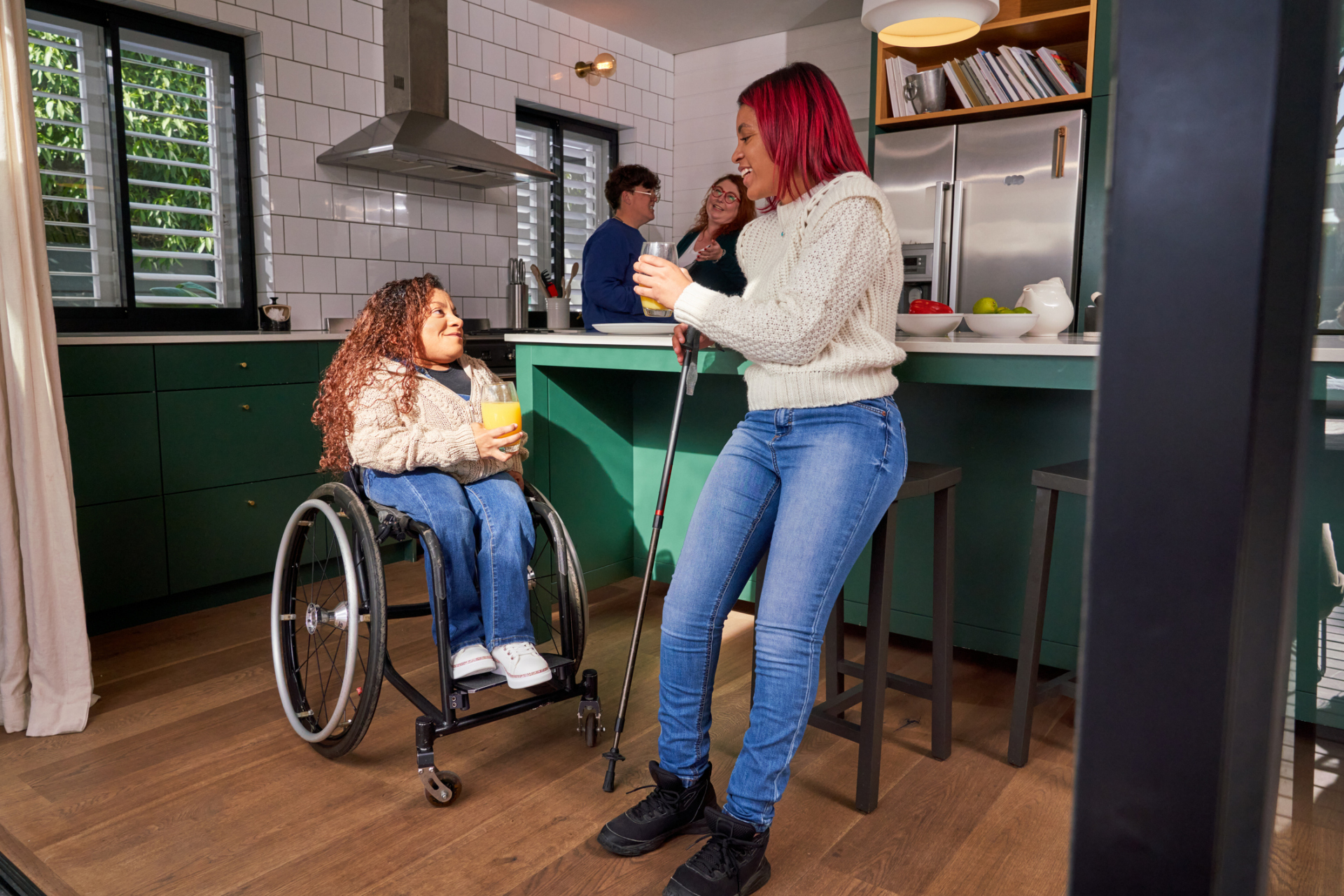Smiling friends with different disabilities talking in the kitchen