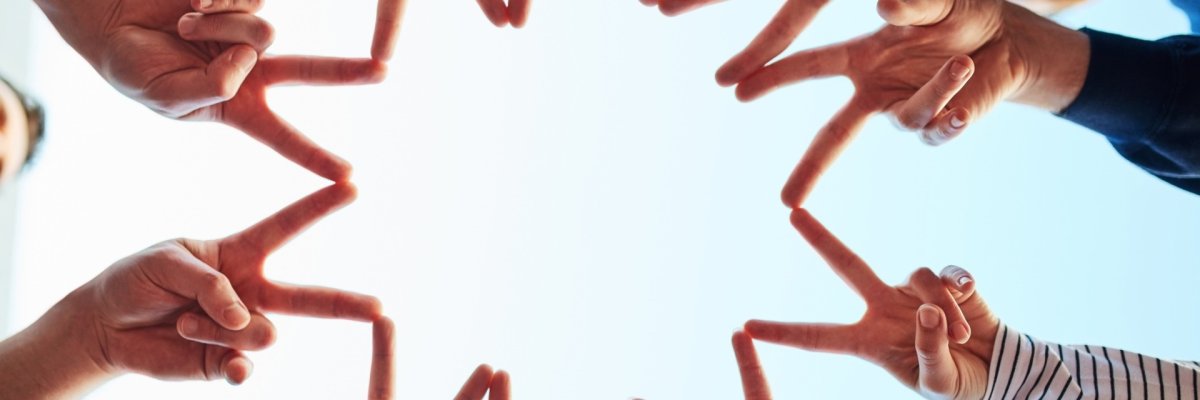 Close-up of a group of people clasping their hands in solidarity