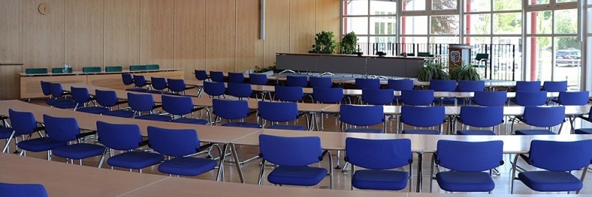 large conference room The picture shows the large meeting room. It was taken from the back row with a view of the podium. You can see blue chairs standing at tables and the podium.