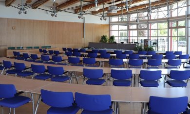 large conference room The picture shows the large meeting room. It was taken from the back row with a view of the podium. You can see blue chairs standing at tables and the podium.