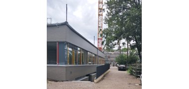 Das Baustellenbild zeigt einen Fassadenteil des Schulzentrums Geretsried. Im Hintergrund steht ein Kran.