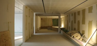 Zu sehen ist ein Flur im Baustellenzustand. Die Wände sind unverputzt. Links sind zwei offene Eingänge zu Klassenräumen zu sehen.