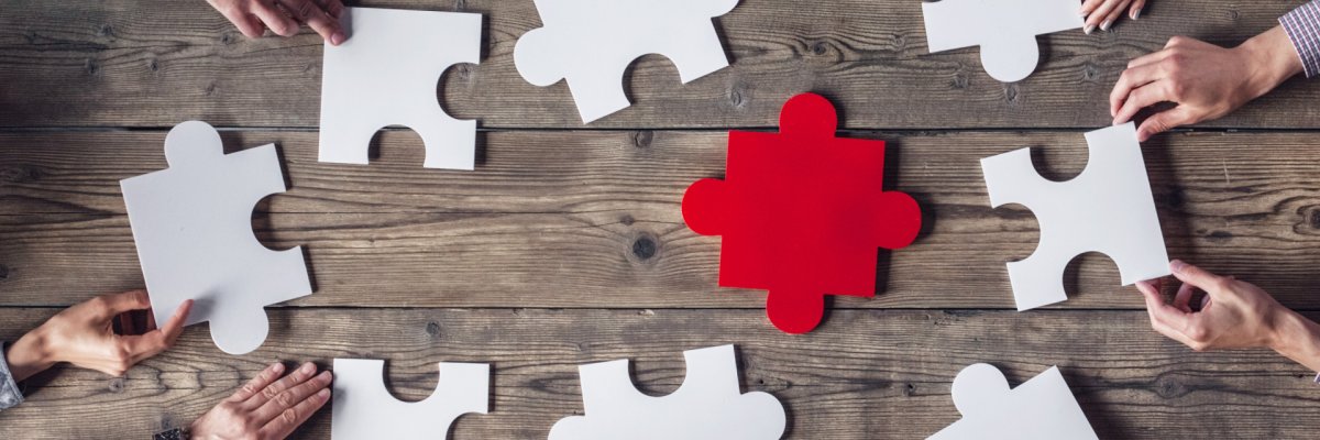 Hände am Tisch mit Puzzleteilen Hände am Tisch mit Puzzleteilen