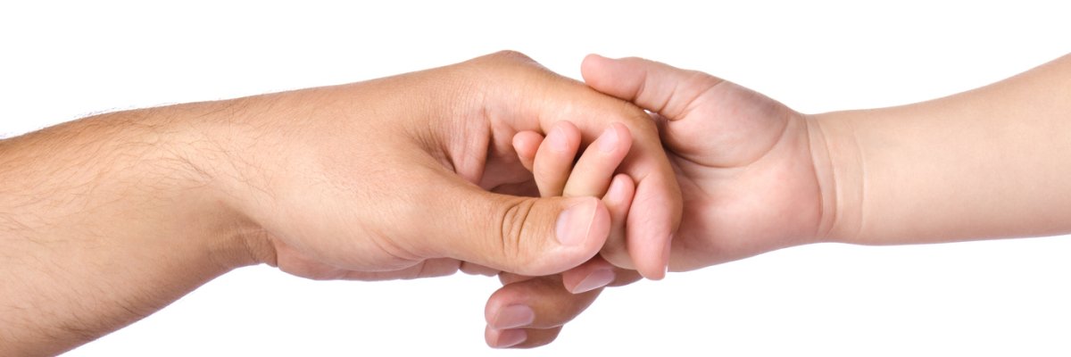Father giving hand to a child Eine Kinderhand greift nach einer Hand von einem Erwachsenen. Verbundenheit und Fürsorge werden sichtbar.