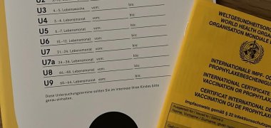 Fotografie eines Untersuchungsheftes für die Vorsorgeunteruntersuchung und des Impfpasses. Beide Hefte sind gelb.